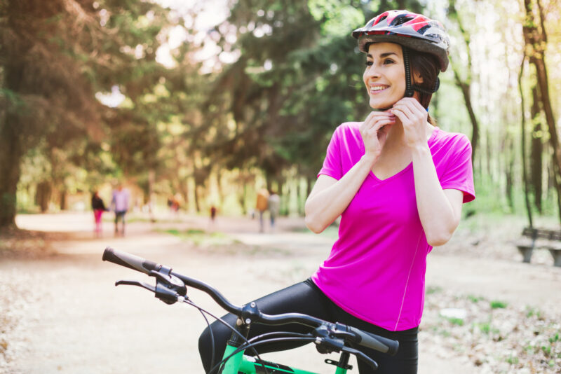 Woman Putting Biking Helmet on Outside During Bicycle Ride.