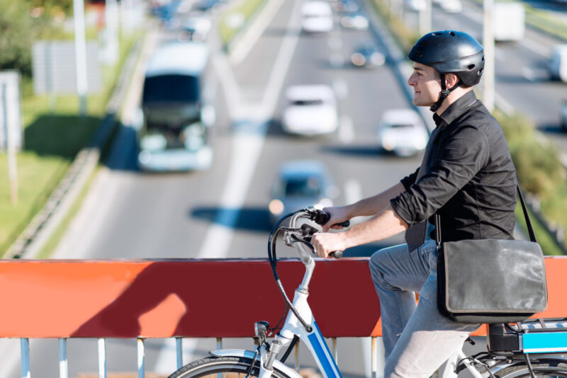 Commuter riding e-bike, crossing overpass