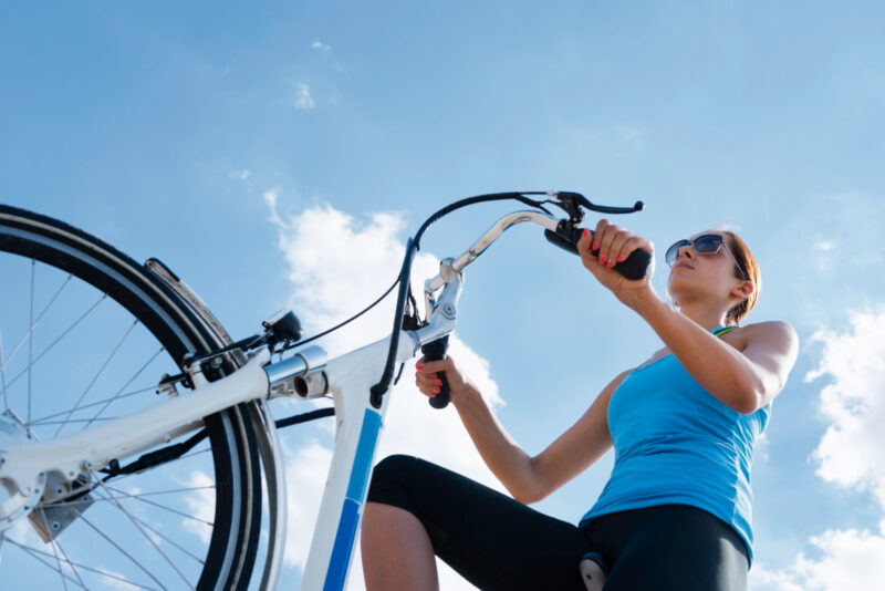 Riding electric bicycle or e-bike, shot against blue sky, convenient copy space